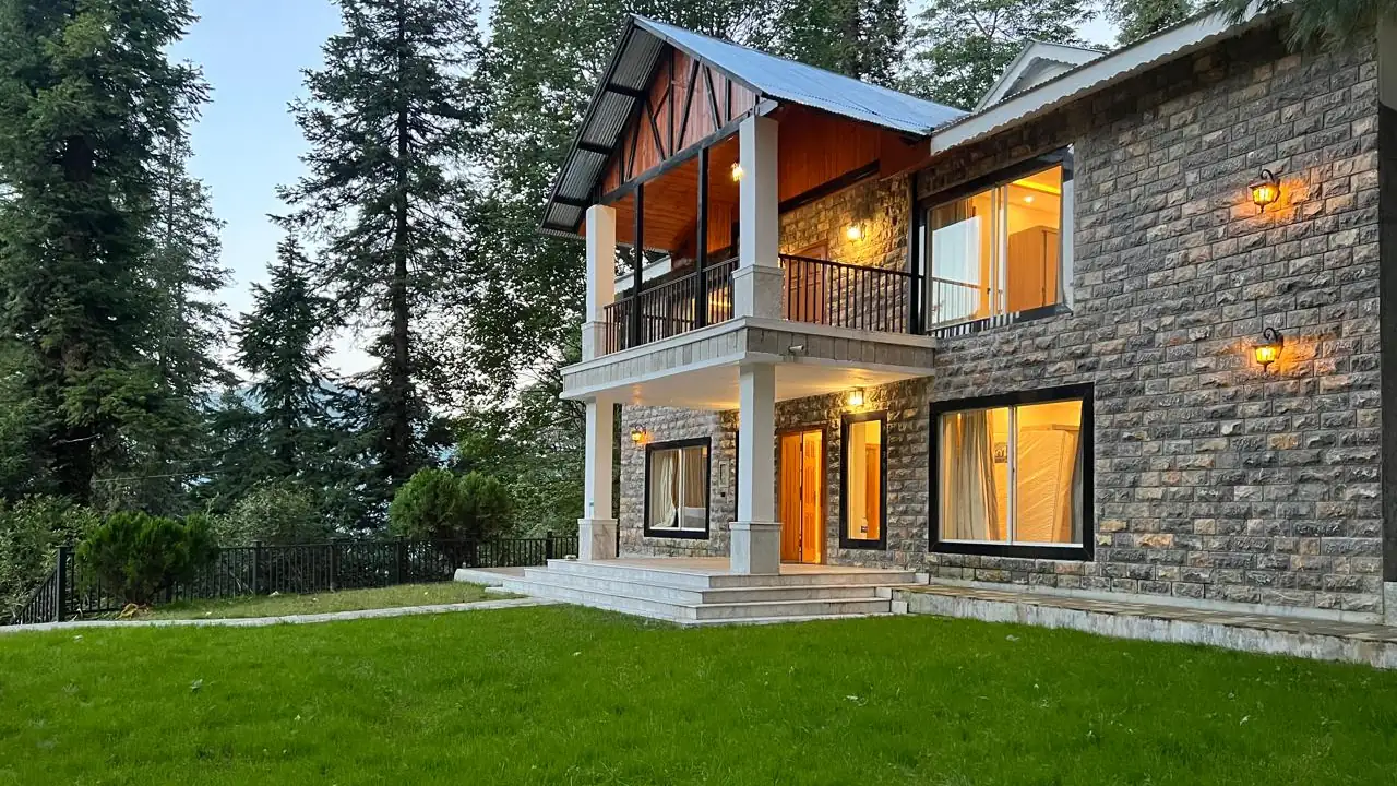 Haven Alpine Villa in Nathia Gali at dusk, a private stone holiday home with a lawn among pine trees